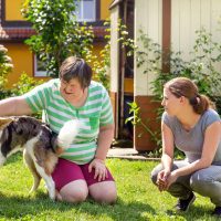 Vrouw met hond en begeleider in de gehandicaptenzorg