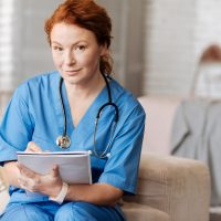 Verpleegkundige zit met notitieblok in haar handen