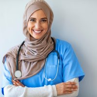 Portret van een vrolijke jonge verpleegkundige met een hoofddoek op